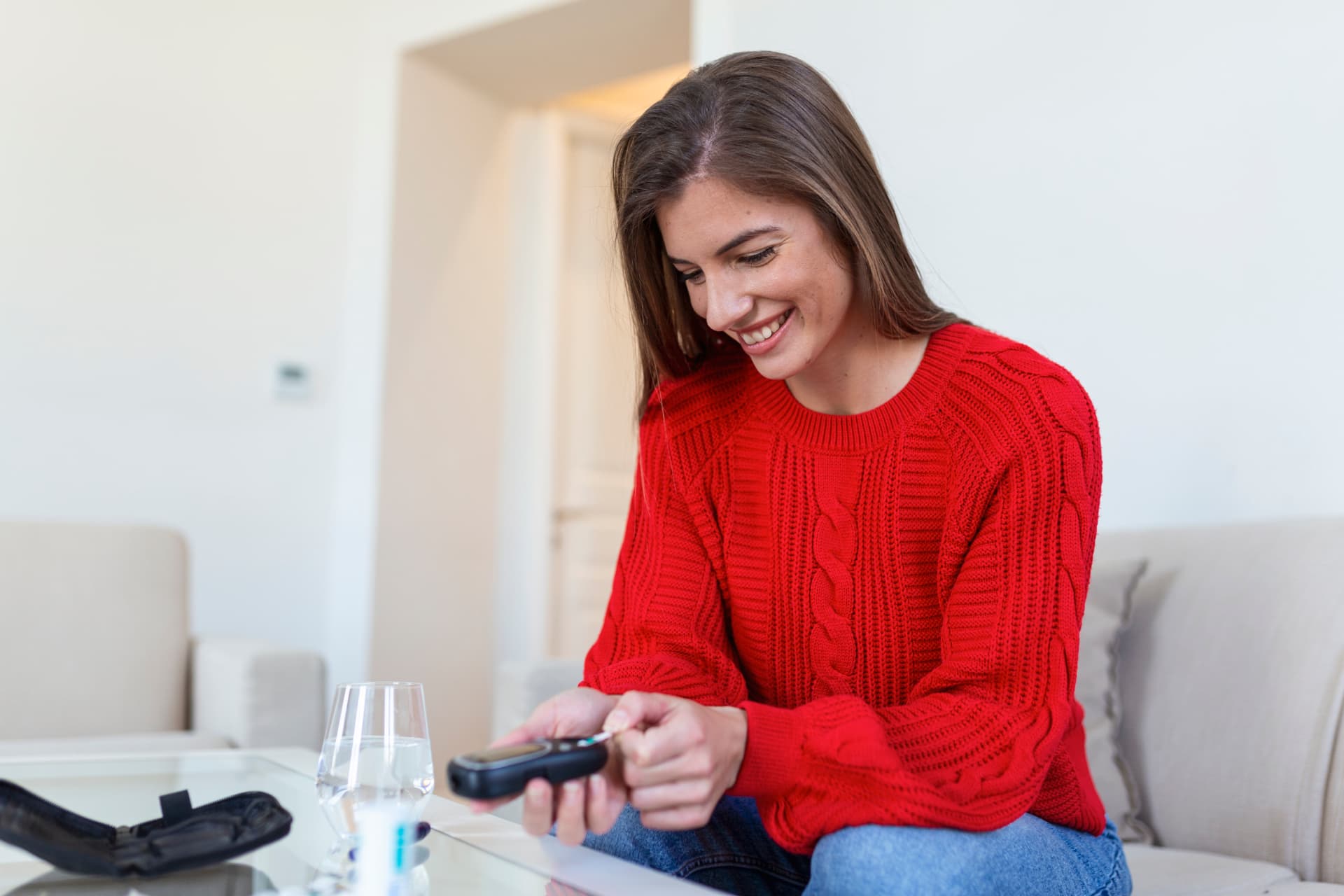 Mujer sonriente realizando una medición de glucosa en casa